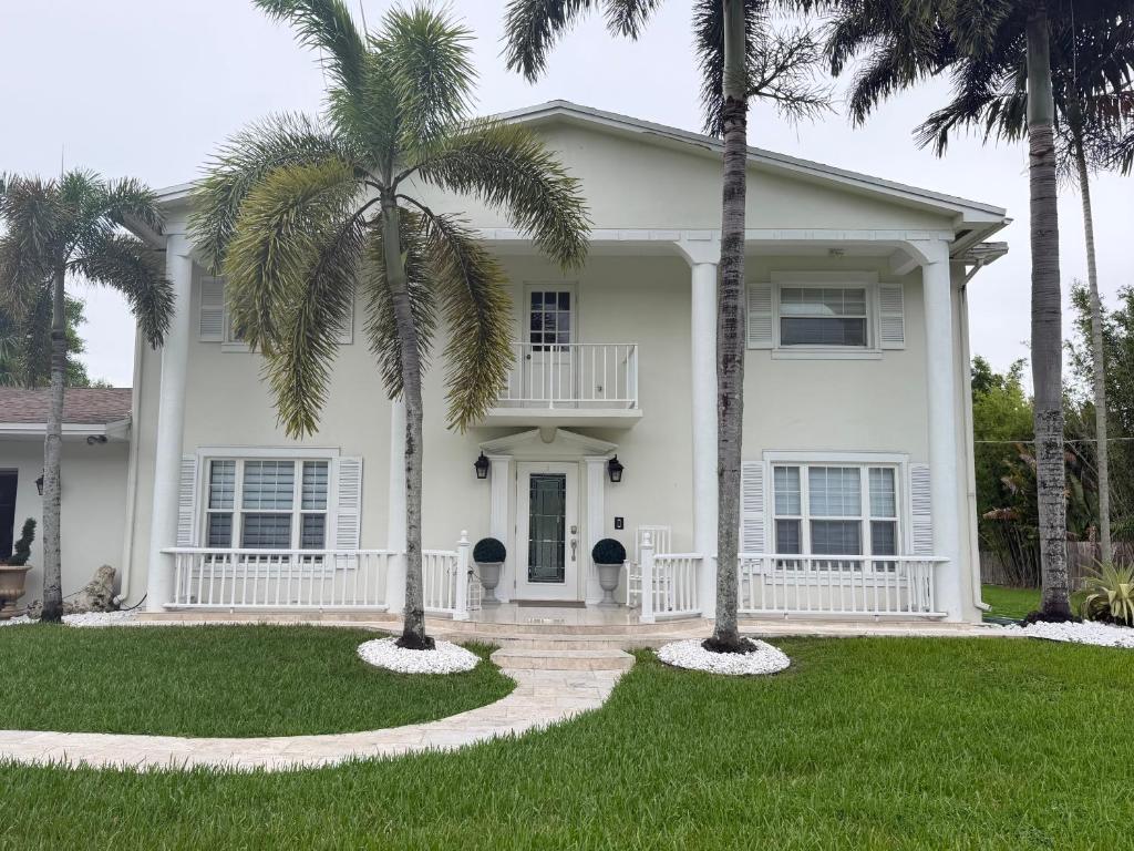 a white house with palm trees in the yard at Homestay Weston Ranches in Southwest Ranches