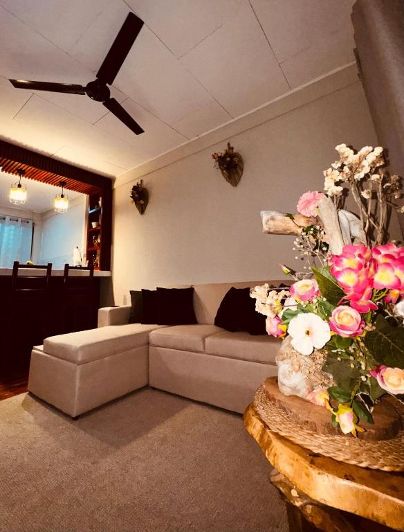 a living room with a couch and flowers on a table at Sweet Home JACÓ in Herradura