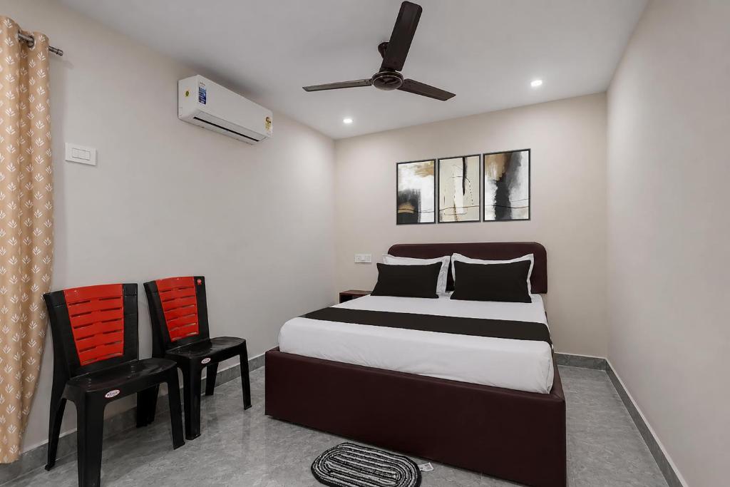 a bedroom with a bed and a chair and a ceiling fan at Hotel O Saikrishna Inn in Rājahmundry