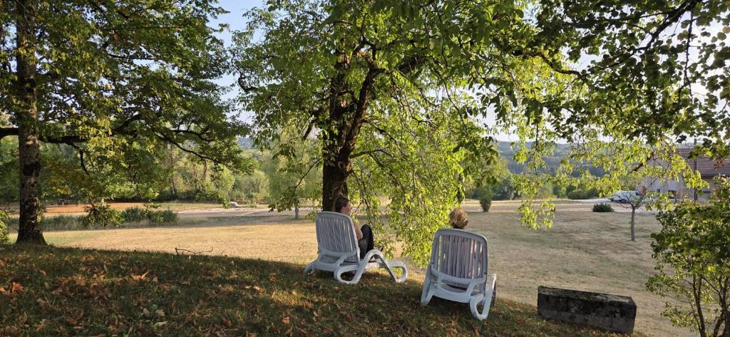 two people sitting in chairs under a tree at Grimont gîte au calme grand terrain circuit cascades du Hérisson in Saugeot