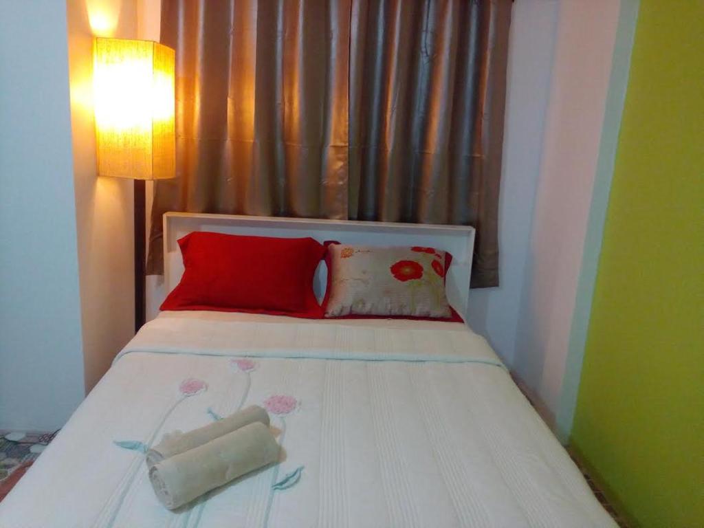 暖武里的住宿－烏薩拜旅館，一间卧室配有红色枕头的床