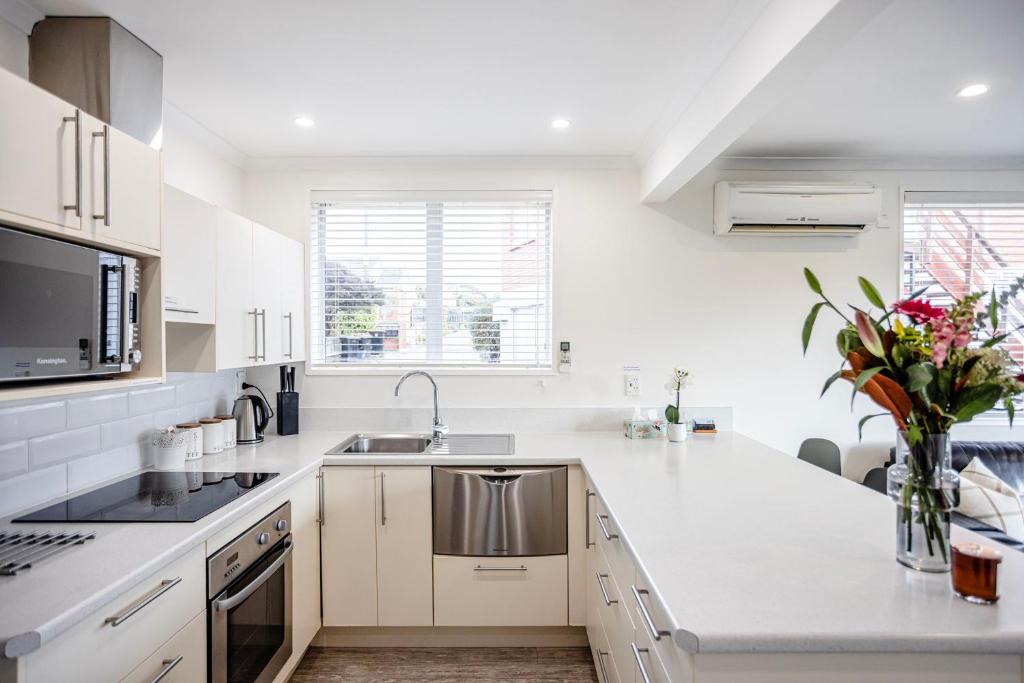 a white kitchen with a sink and a counter at Roslyn Sanctuary Hereford St Dunedin in Dunedin