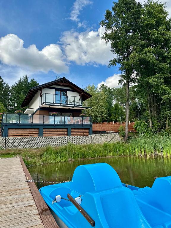 a house on a dock with a boat in the water at Szept Wody Kaszuby in Lubiana