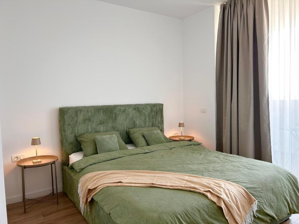 a bedroom with a green bed with two end tables at V'One - Cozy & Quiet Apartment - Free Parking in Timişoara