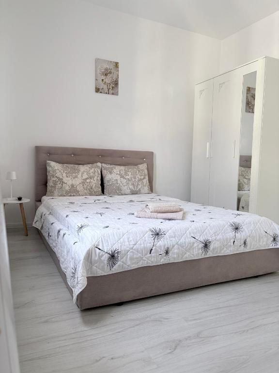 a bedroom with a large bed with white sheets and a mirror at Bella Home Residence in Roşu