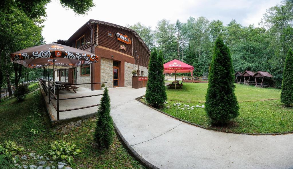 a building with an umbrella next to a park at Moto pub Marusja in Snina