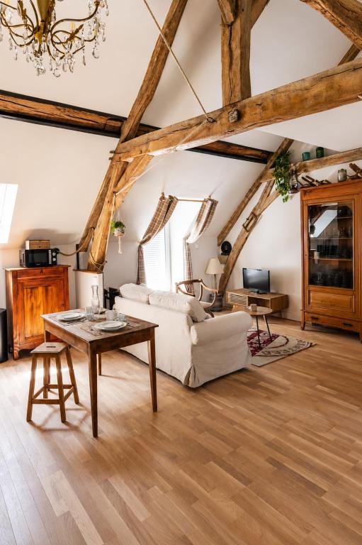 a living room with a white couch and a table at Le Grenier - Air conditioning - Free parking in Nogent-sur-Vernisson