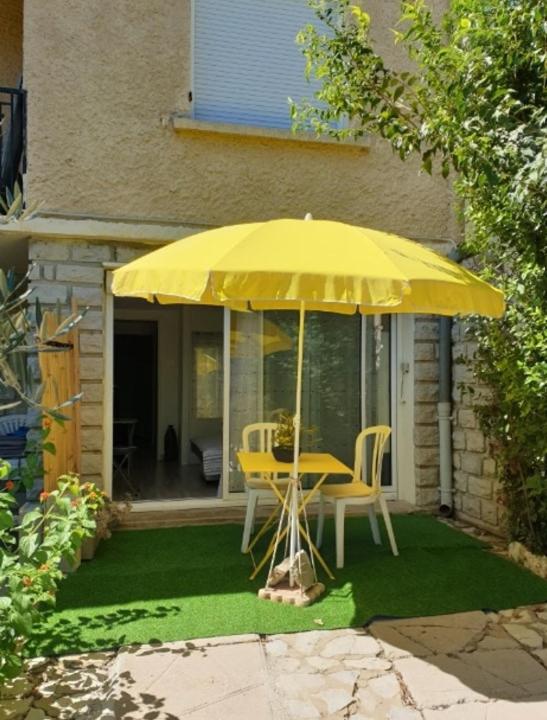 a yellow table and chairs under a yellow umbrella at Renovated studio in Le Crès in Le Crès
