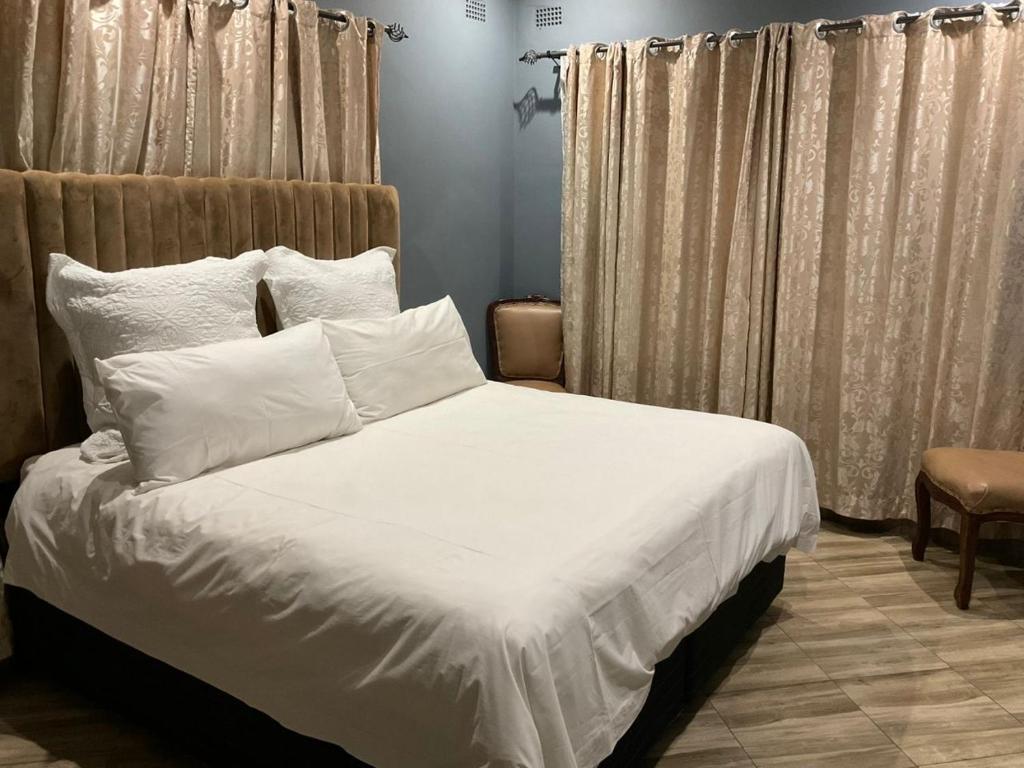 a bedroom with a bed with white sheets and pillows at Zahara Lodge in Victoria Falls