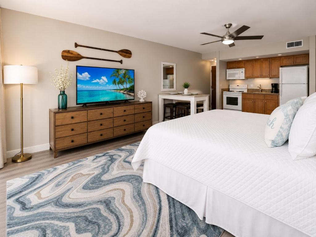 a bedroom with a white bed and a flat screen tv at Royal Kahana 318 Studio Condo in Kahana