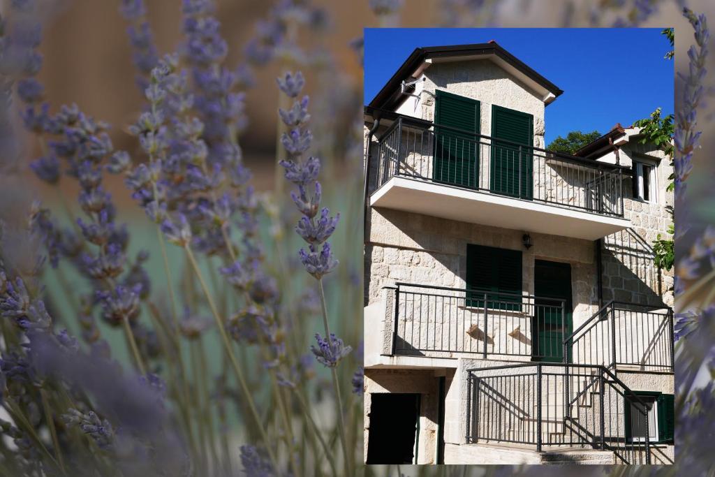 a white building with green windows and a balcony at Kuća za odmor Mate 