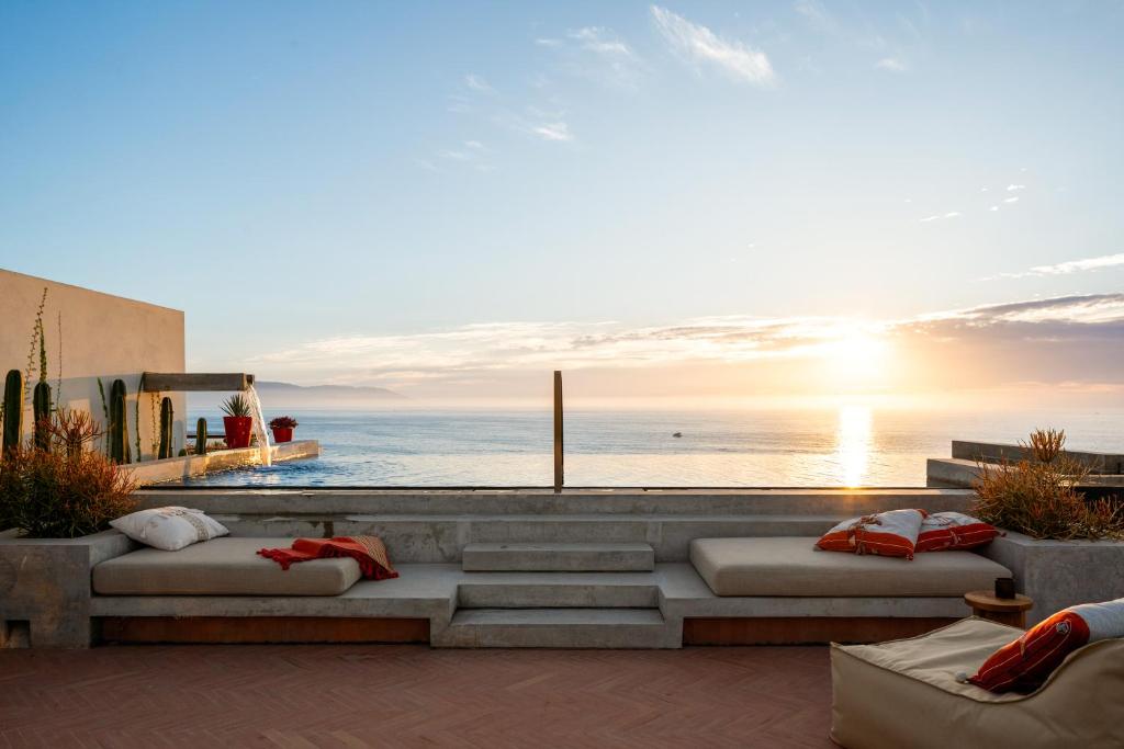 a patio with a view of the ocean at sunset at The Tryst Puerto Vallarta LGBT Hotel in Puerto Vallarta