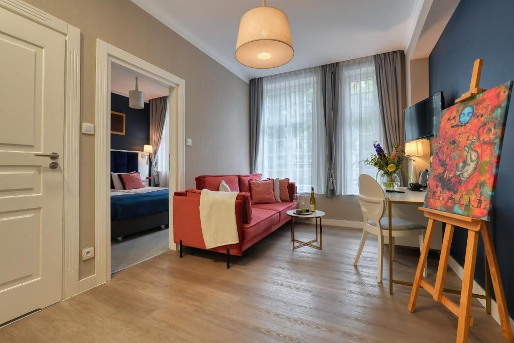a living room with a red couch and a bedroom at Hotel Villa Art Novis Wrocław Centrum in Wrocław