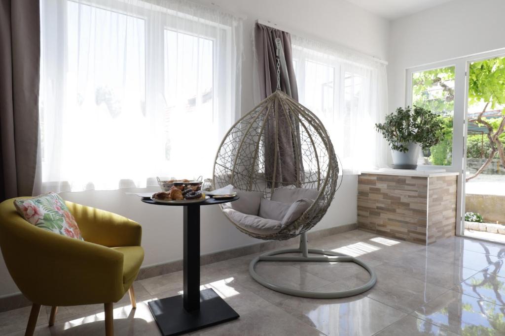 a living room with a swing chair and a table at Amaryllis in Rogoznica
