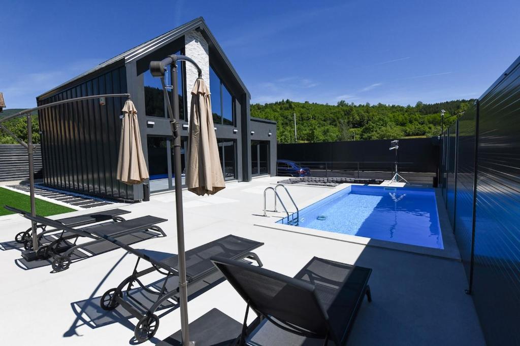 a patio with chairs and umbrellas next to a pool at Luxury Villa with a Private Pool in Hadžići