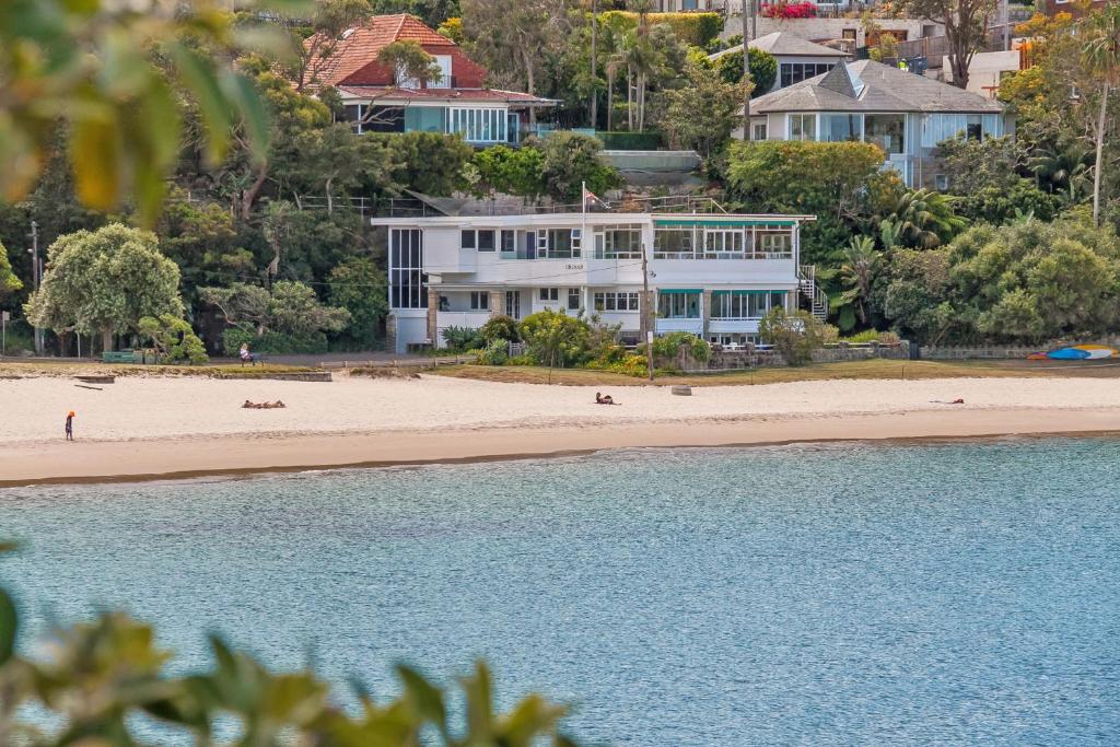 a large white house on the beach next to the water at The Oriana in Sydney