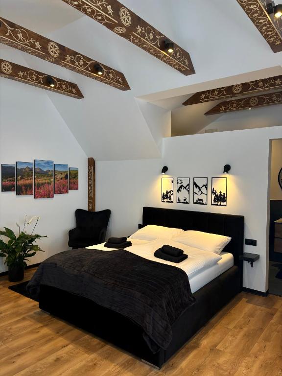 a bedroom with a large bed with white walls at Apartamenty u Gąsiorów in Biały Dunajec