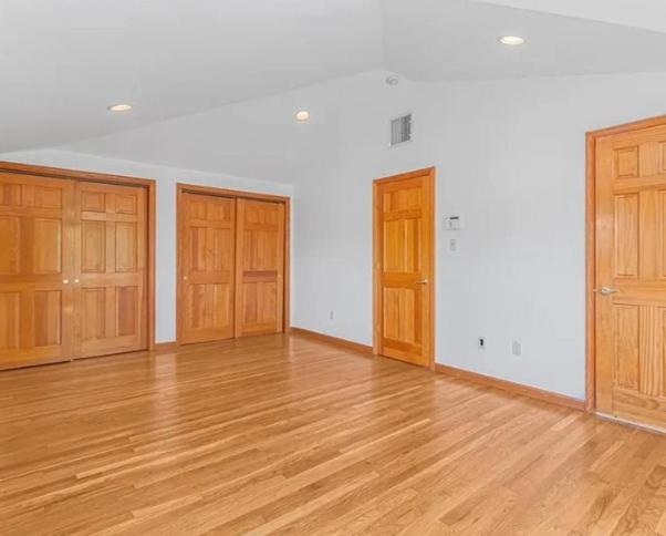 ein leerer Raum mit Holzboden und Holztüren in der Unterkunft Nyc condo in Oakland Gardens