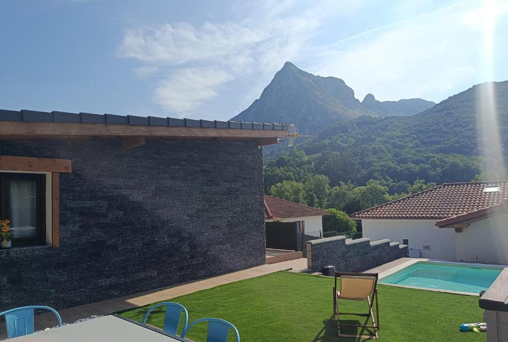 a house with a yard with a swimming pool and mountains at El Paraíso de Aitana in Ramales de la Victoria