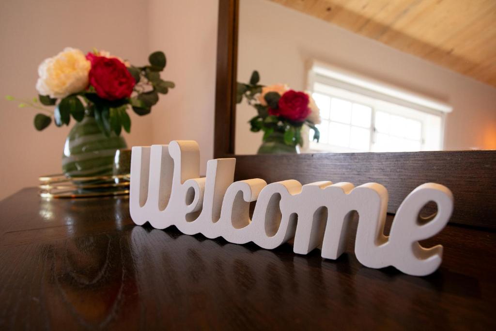 a wooden sign that says shine on a table with flowers at Refúgio das Tílias in Santiago de Litém