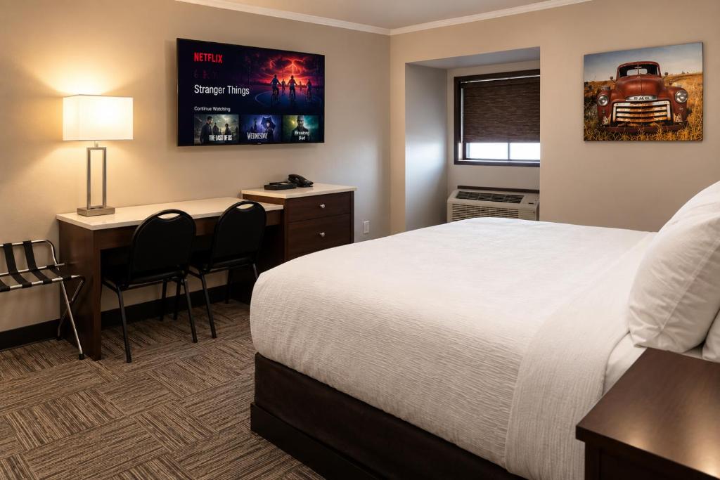 a hotel room with a bed and a desk at Homestead Inn & Suites in Vanderhoof
