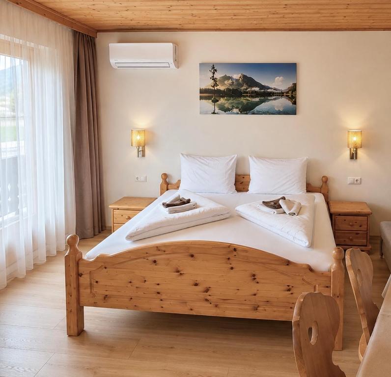 a bedroom with a large wooden bed with white sheets at Haus Seerose in Seeboden