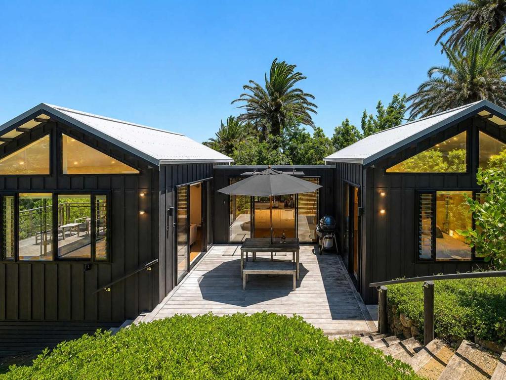 a black house with a table and an umbrella at Art Lovers Retreat - Stay Waiheke in Onetangi
