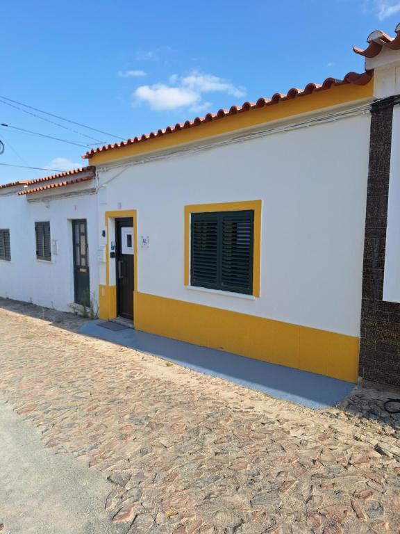a white and yellow house with a cobblestone street at Casa 3 Chamines in Vila Alva