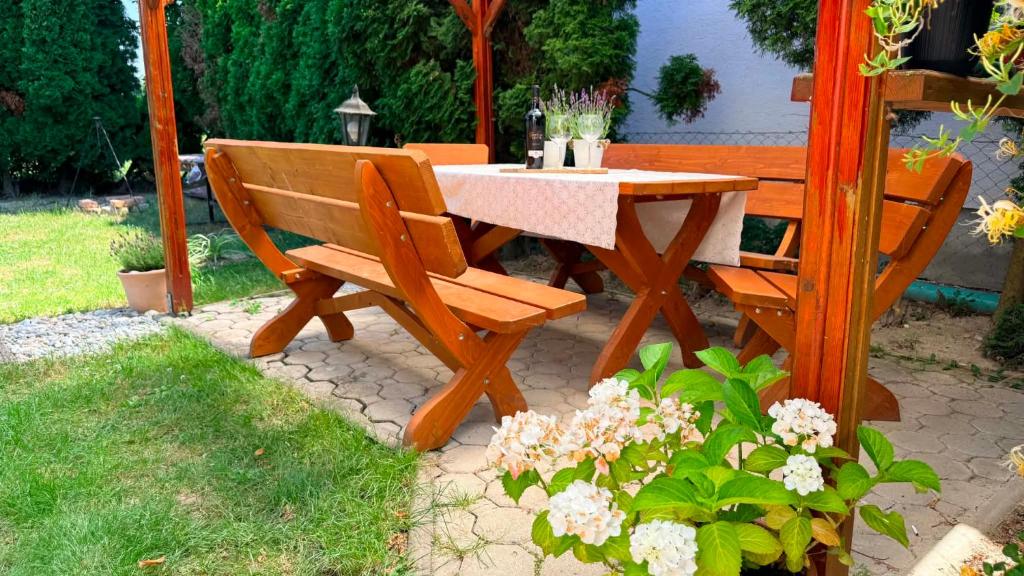 a wooden table and bench next to a table and flowers at Rebeka Vendégház in Dunasziget