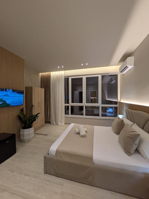 a bedroom with a large bed and a flat screen tv at Todo Luxury Suites in Durrës