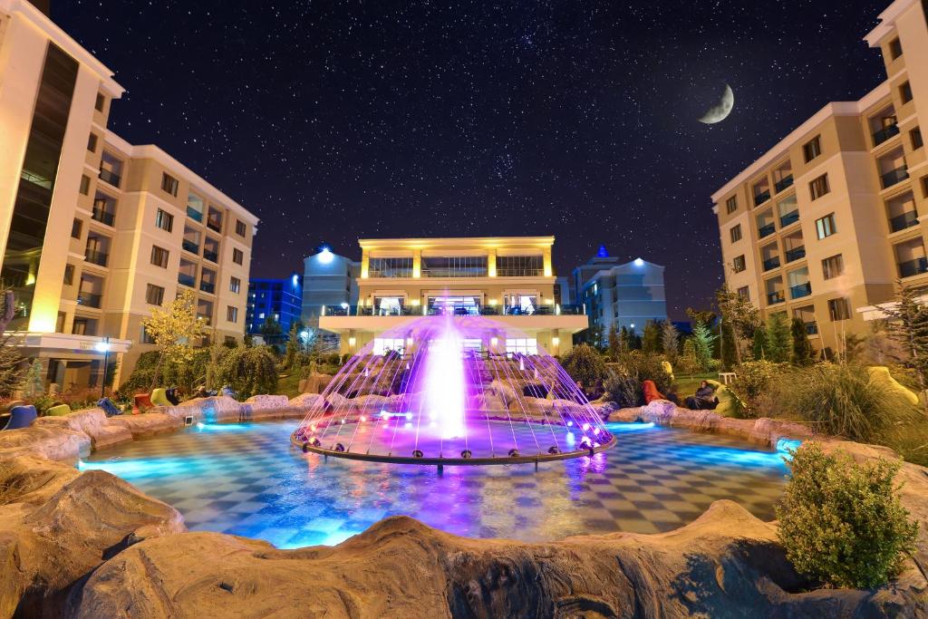 una fuente frente a un edificio por la noche en Grand Ozgul Thermal Holiday Village en Gazligol