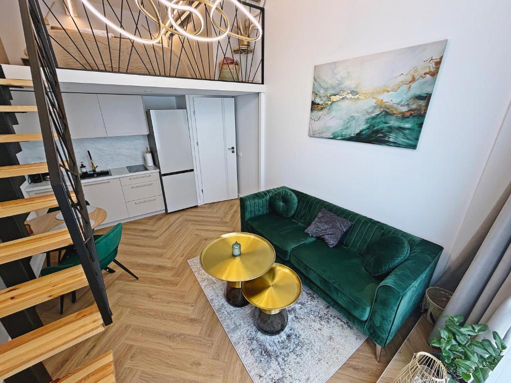 a living room with a green couch and a table at The Emerald Loft I Terrace I Free Parking in Kaunas