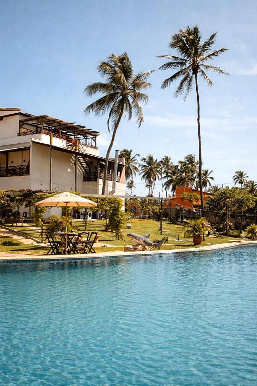 a swimming pool with palm trees and a building at Pousada Varanda Amar - Icaraizinho de Amontada in Icaraí