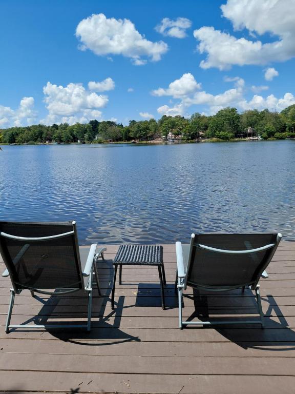 two chairs and a table on a dock near a lake at LAKEFRONT CHALET in THE BURCHES in Tobyhanna