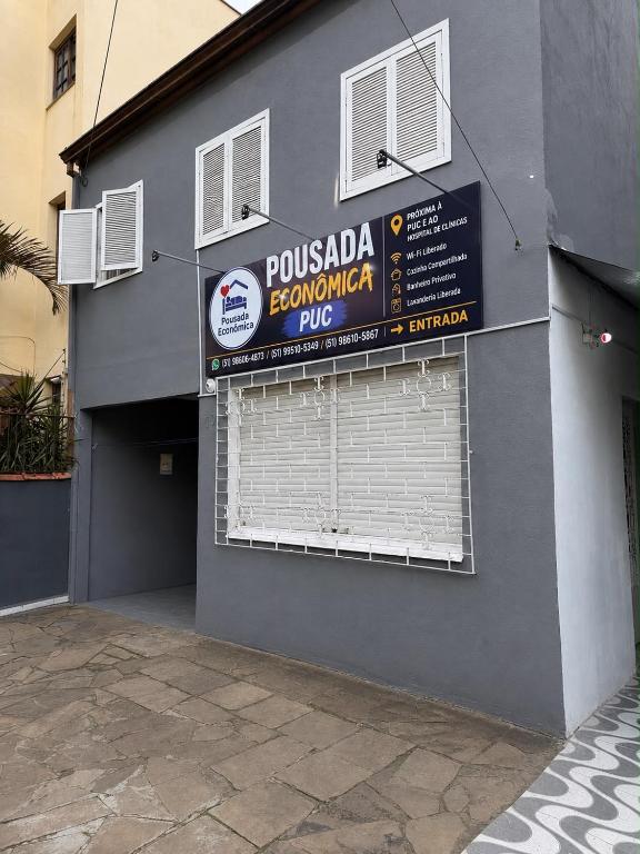 a sign on the side of a building with a garage at Pousada econômica puc in Porto Alegre