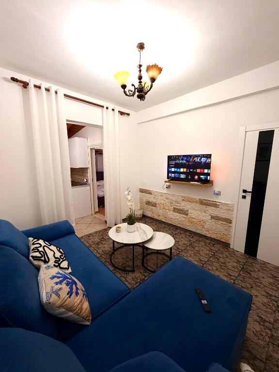 a living room with a blue couch and a tv at Green Door House in Vlorë