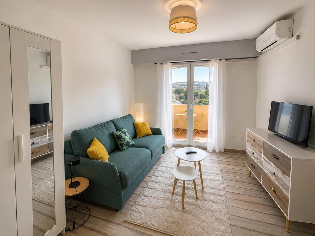 a living room with a green couch and a television at Lovely studio with balcony - central location in Cavalaire-sur-Mer