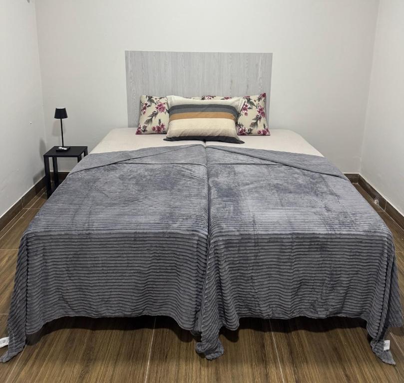 a bed with a gray blanket on top of it at Maia Hostel in Várzea Grande