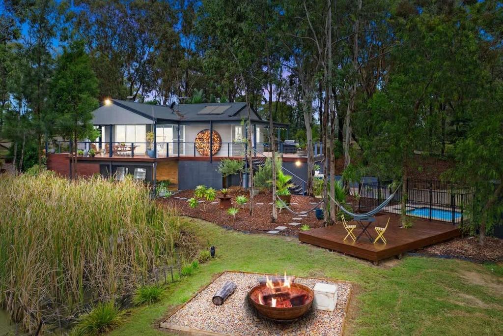 a large house with a hammock in the yard at Fig Tree Luxury Guest House in Pokolbin