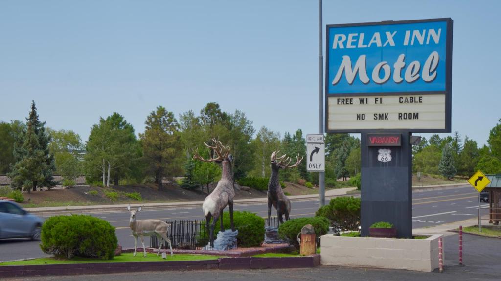 a sign with statues of giraffes and a motel at Relax Inn in Flagstaff
