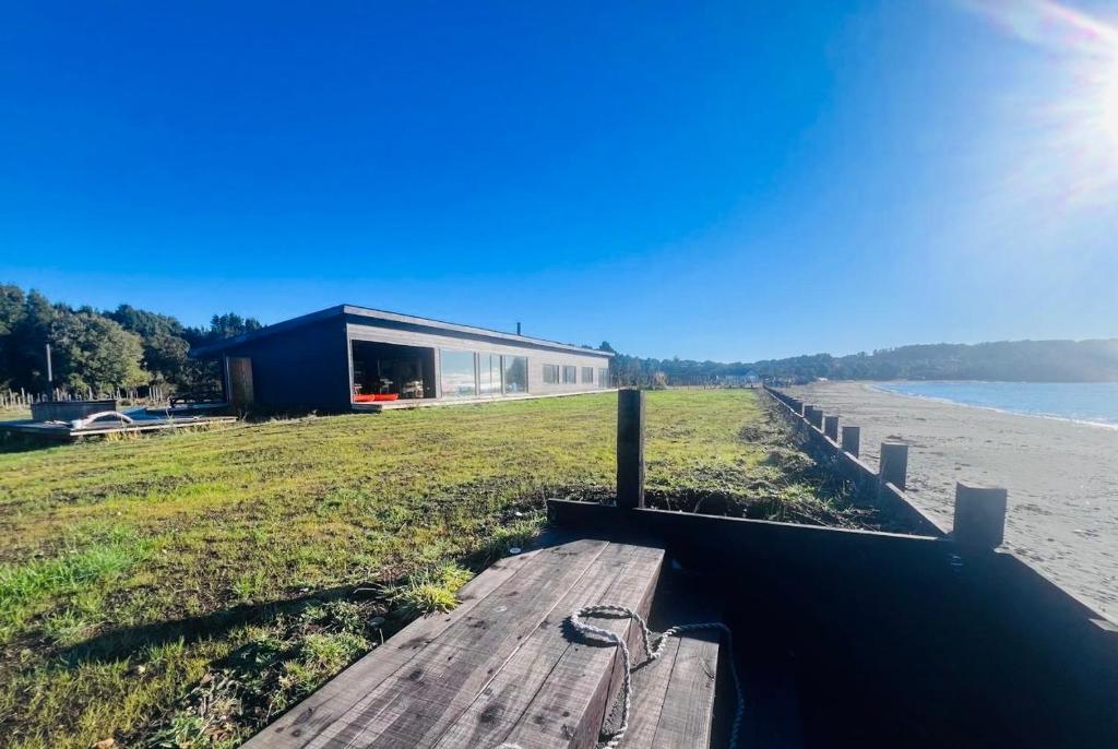 a house on the beach with a wooden dock at Casa orilla playa en Chiloé in Aytuy