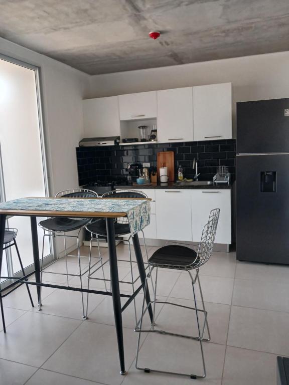 a kitchen with a table and chairs and a refrigerator at Departamento en Condominio in Luque