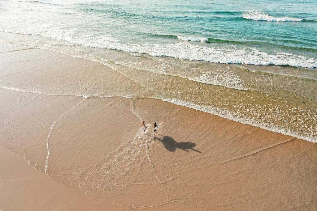 two people standing on a beach near the ocean at 41 Ocean in Anna Bay