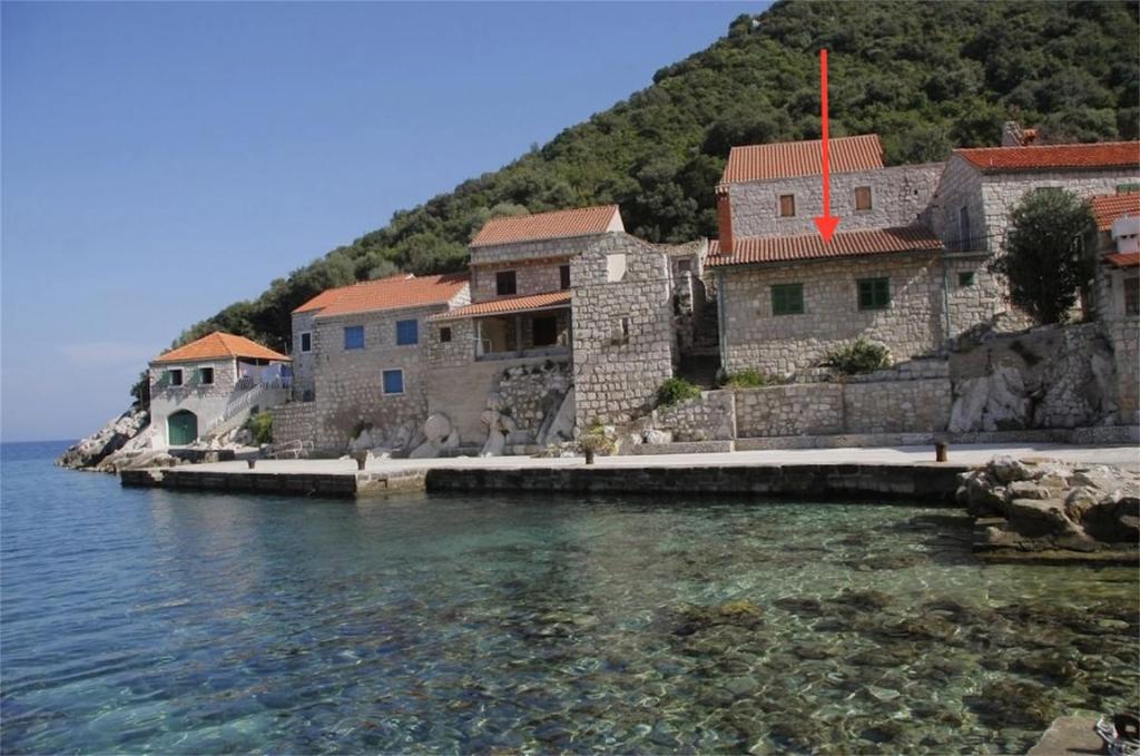 a group of houses on a hill next to the water at Lucica 1 Beachfront House in Lastovo