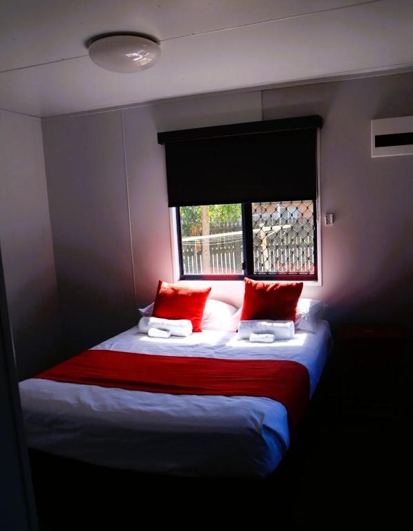a bedroom with a bed with red pillows and a window at The Hotel Pioneer Brandon in Brandon