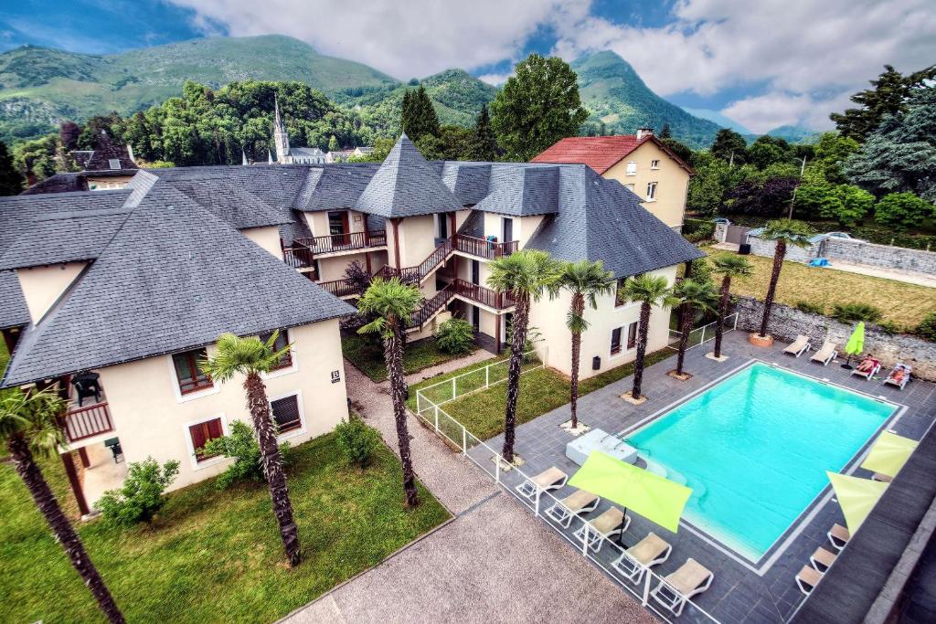 an aerial view of a house with a swimming pool and palm trees at Comfort Aparthotel Lourdes L'Acacia in Lourdes