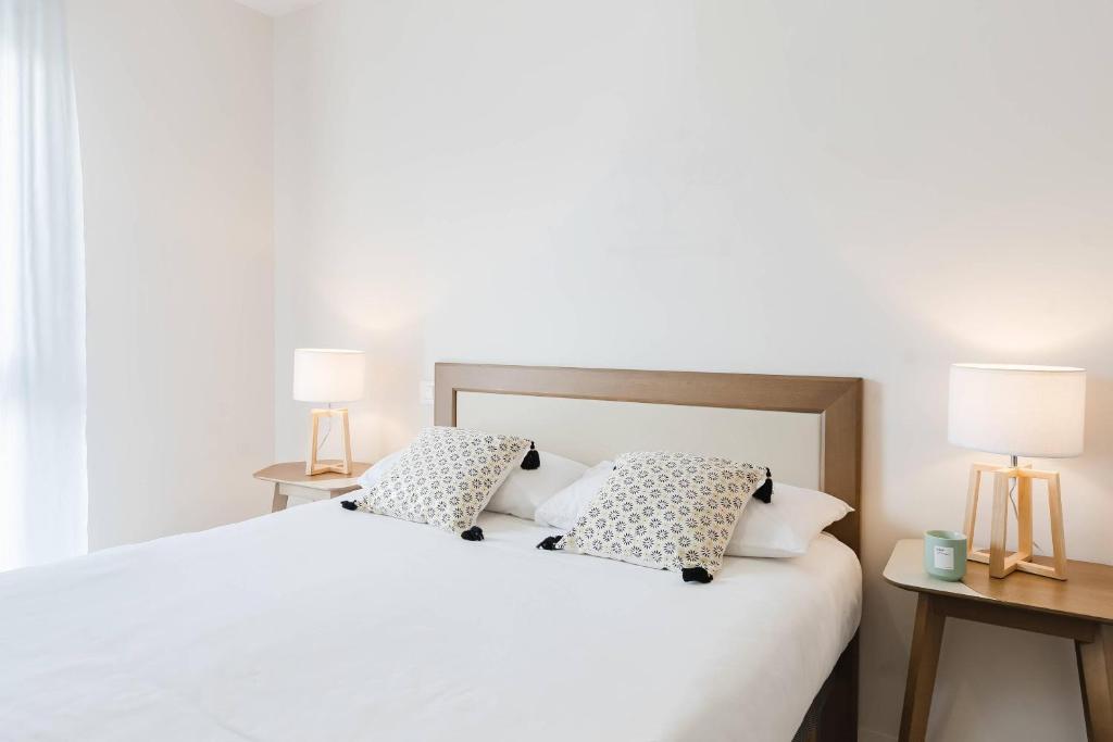 a bedroom with a white bed with two lamps at Quality Aparthotel Dinan in Dinan