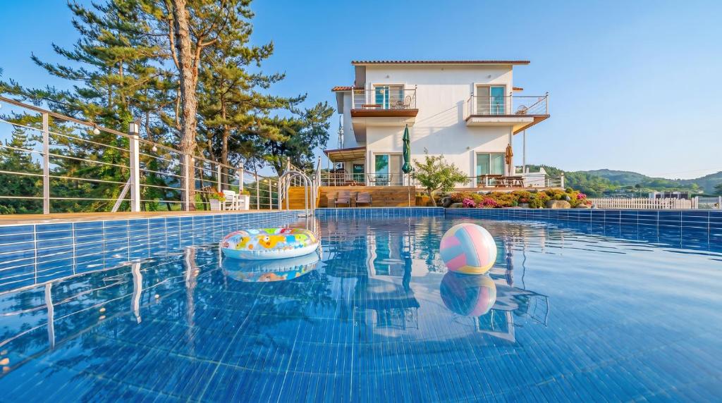 a swimming pool with a house in the background at Yeosu Sky Pension in Yeosu