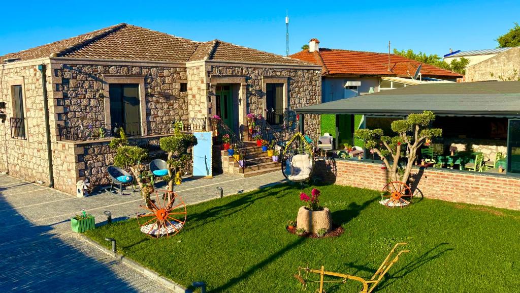 a house with a yard with trees and chairs at Mlinova Küçükköy in Ayvalık