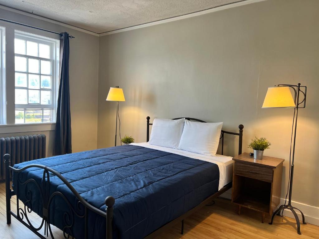 a bedroom with a bed with a blue blanket and two lamps at Grand Union Hotel in Coleman